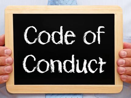 Hands holding chalkboard, text reads 'Code of Conduct'